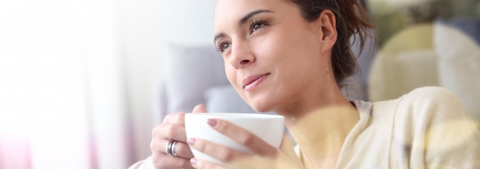 Peaceful woman relaxing at home with cup of tea