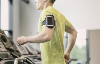 man with smartphone exercising on treadmill in gym