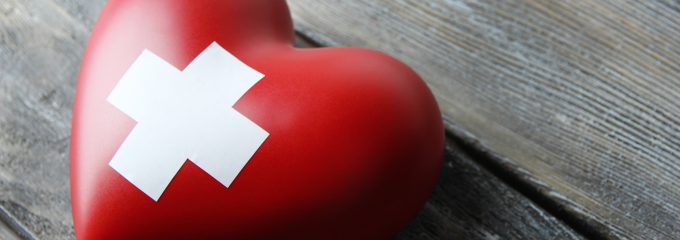 Red heart with cross sign on wooden background