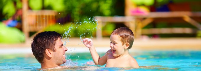 joyful father and son having fun in pool, summer holidays