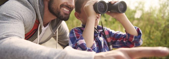 father and son looking through binoculars